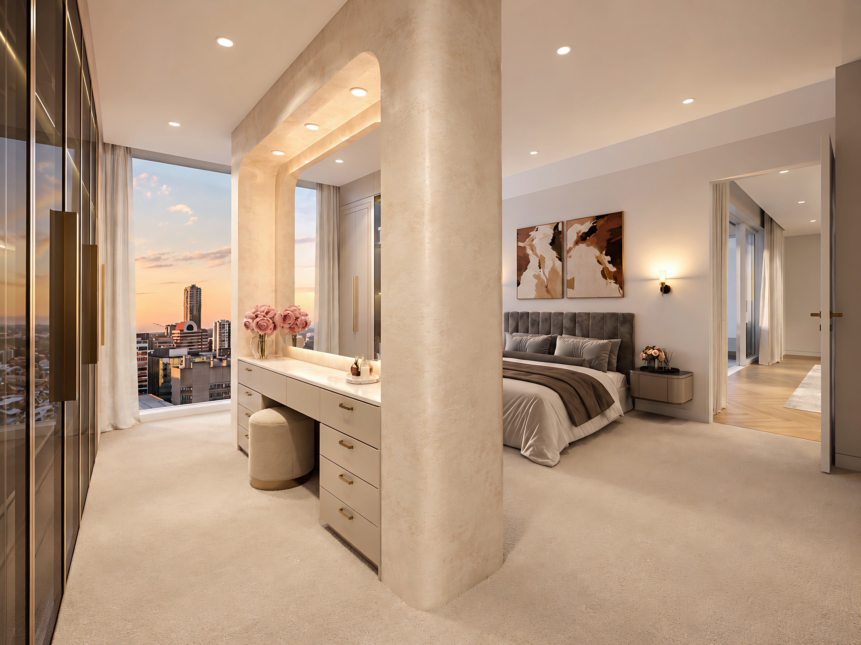 Dressing area behind the walk-in robe partition, with an arched lit mirror, vanity and stool, the bedroom and the city at sunset beyond.