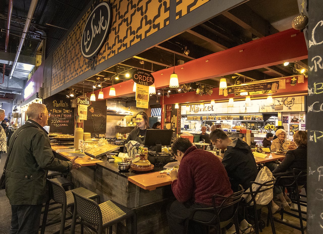 Diners at a busy food counter inside the Adelaide Central Market.