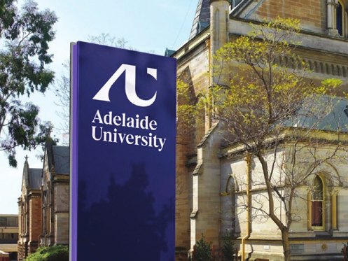 Adelaide University signage beside its sandstone buildings.